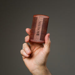 Mão segurando Pente Duplo de Madeira para Barba Robusta
